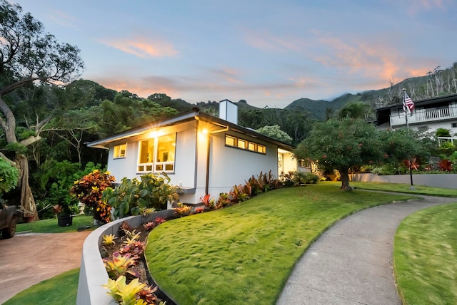 exterior space with a lawn, a chimney, and a mountain view