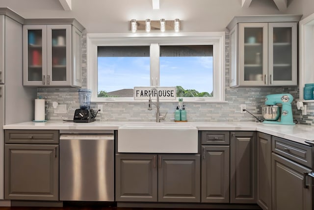 kitchen with stainless steel dishwasher, gray cabinets, decorative backsplash, and a sink