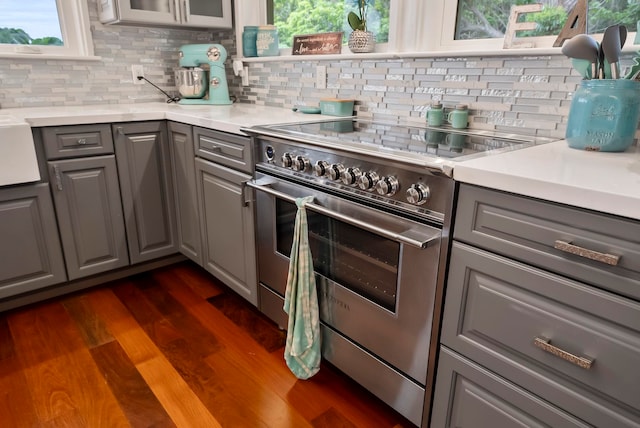 kitchen with dark wood-type flooring, light countertops, high end stove, and gray cabinets