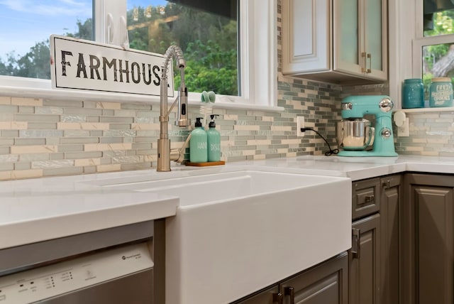 kitchen featuring light countertops, a sink, dishwasher, decorative backsplash, and dark brown cabinets