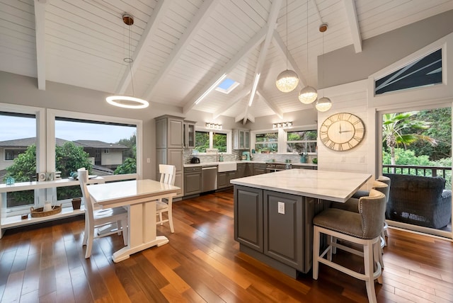 kitchen with stainless steel dishwasher, gray cabinetry, a notable chandelier, and a kitchen bar