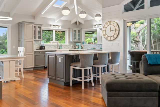 kitchen featuring light countertops, gray cabinets, tasteful backsplash, and glass insert cabinets