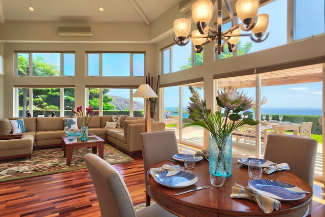 sunroom featuring an inviting chandelier, lofted ceiling, a wall mounted air conditioner, and a water view