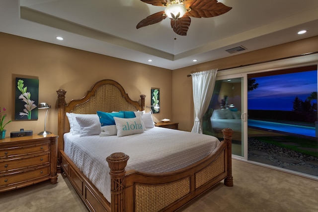 bedroom with a raised ceiling, ceiling fan, and light carpet