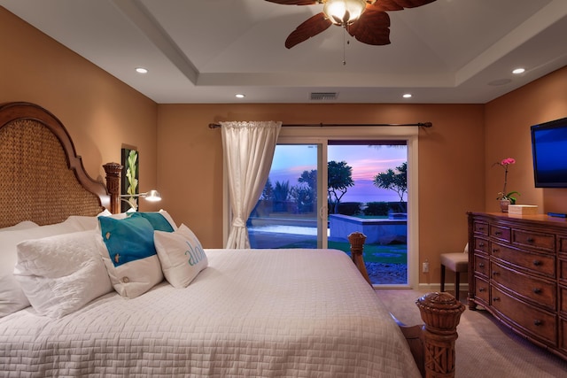 carpeted bedroom with ceiling fan, a tray ceiling, and access to exterior