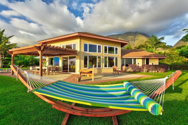 rear view of property featuring a lawn, a pergola, and a patio area