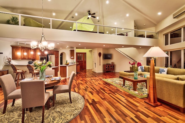 dining space featuring high vaulted ceiling, hardwood / wood-style flooring, and ceiling fan with notable chandelier