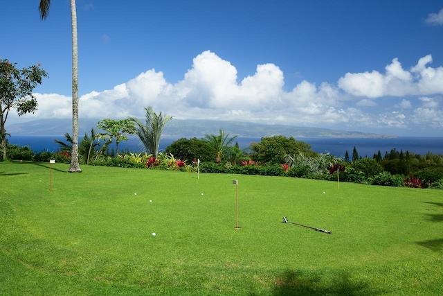 view of home's community featuring an area to practice putting and a water view