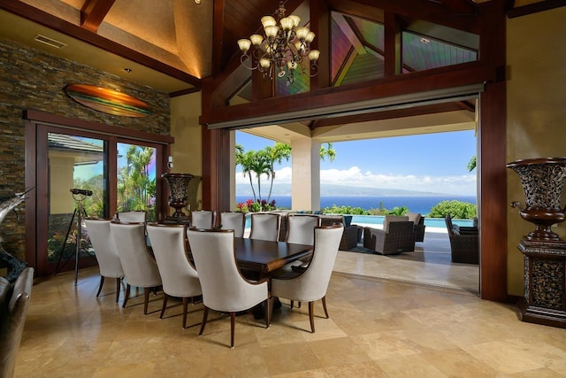 dining space with a water view, a towering ceiling, plenty of natural light, and a chandelier