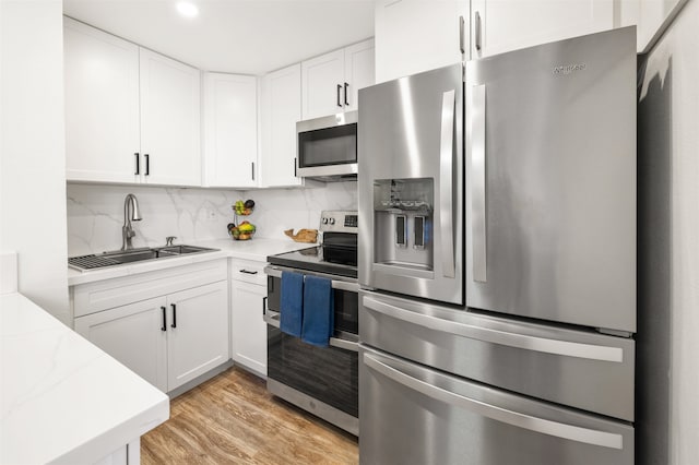 kitchen featuring appliances with stainless steel finishes, white cabinetry, sink, and light wood-type flooring