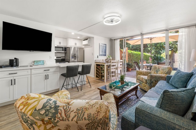 living room featuring an AC wall unit and light wood-type flooring