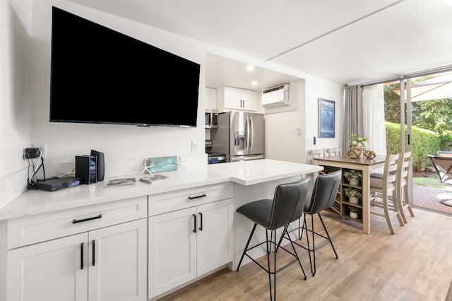 kitchen featuring appliances with stainless steel finishes, white cabinets, an AC wall unit, and light hardwood / wood-style floors