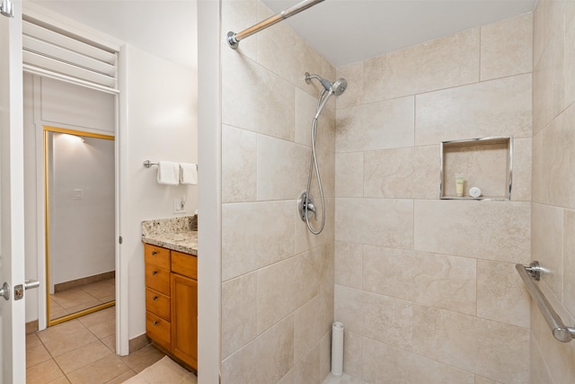 full bathroom featuring a tile shower, vanity, and tile patterned floors