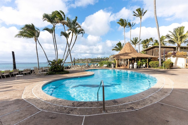 view of pool with a patio and a water view