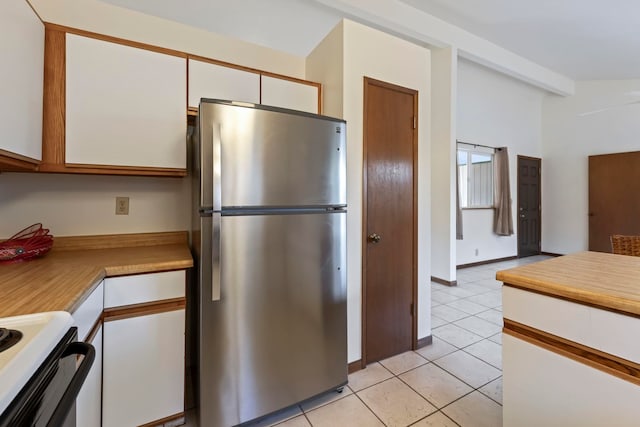 kitchen featuring light tile patterned flooring, range with electric stovetop, white cabinets, and stainless steel refrigerator