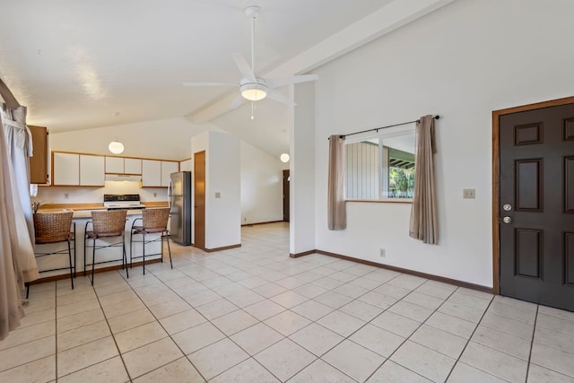 kitchen featuring light tile patterned floors, kitchen peninsula, stainless steel fridge, beam ceiling, and a breakfast bar