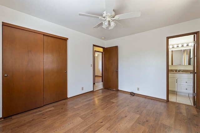 unfurnished bedroom with ceiling fan, a closet, connected bathroom, and wood-type flooring