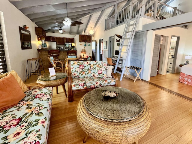 living room with beamed ceiling, ceiling fan, high vaulted ceiling, and light hardwood / wood-style flooring