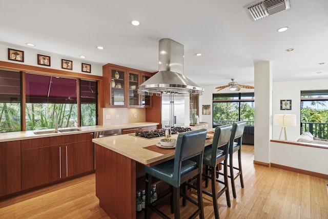 563 Mikioi Pl, Kihei, HI 96753 - kitchen featuring island exhaust hood, gas cooktop, light countertops, light wood-style flooring, and a kitchen breakfast bar