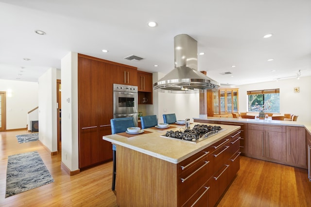563 Mikioi Pl, Kihei, HI 96753 - kitchen with stainless steel gas cooktop, island range hood, a kitchen island, light wood-type flooring, and recessed lighting
