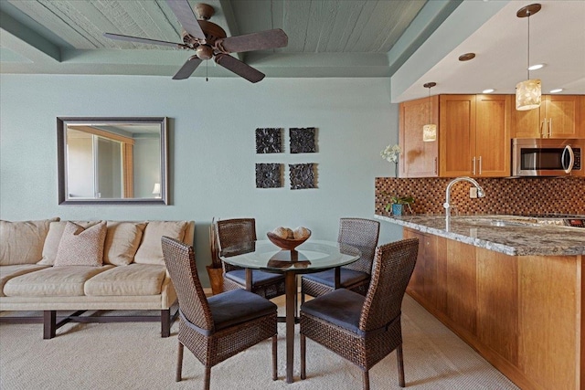 dining area featuring ceiling fan, sink, and light colored carpet