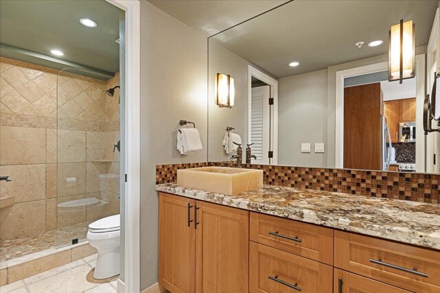 bathroom featuring a shower, vanity, toilet, and backsplash