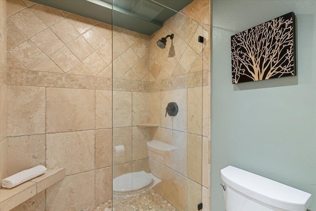 bathroom featuring a tile shower and toilet