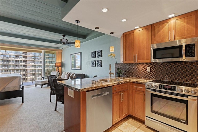 kitchen featuring sink, stainless steel appliances, kitchen peninsula, decorative light fixtures, and light carpet