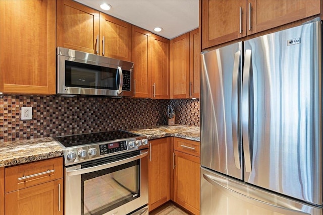 kitchen with light stone countertops, appliances with stainless steel finishes, and tasteful backsplash