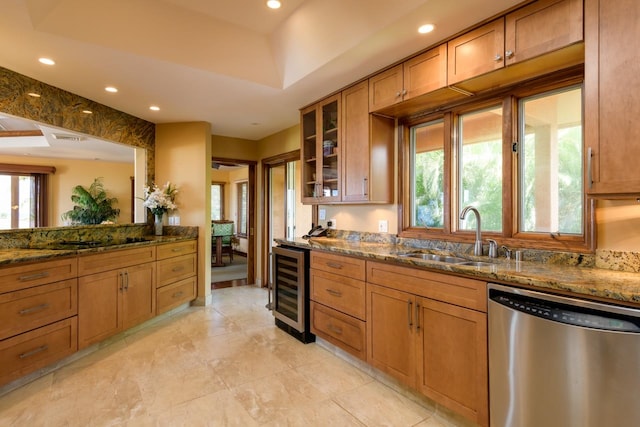 kitchen with light tile flooring, stainless steel dishwasher, dark stone countertops, and sink