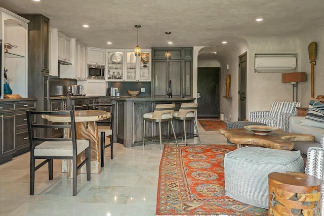 12 S Kihei Rd Unit E2, Kihei, HI 96753 - kitchen featuring stainless steel microwave, an AC wall unit, glass insert cabinets, recessed lighting, and pendant lighting