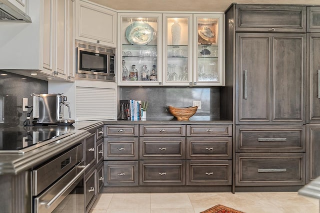 12 S Kihei Rd Unit E2, Kihei, HI 96753 - kitchen featuring stainless steel appliances, dark brown cabinetry, light tile patterned flooring, dark countertops, and glass insert cabinets