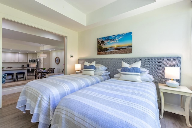 bedroom with a tray ceiling and wood-type flooring