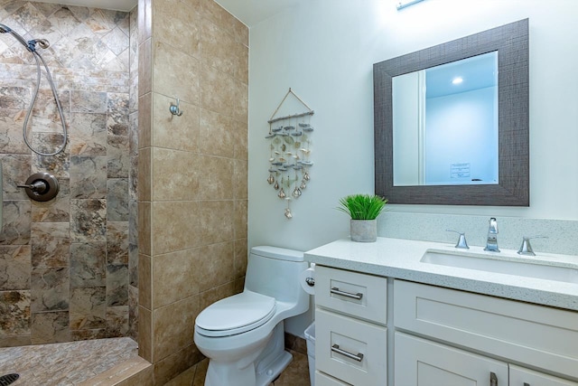 bathroom featuring a tile shower, vanity, and toilet