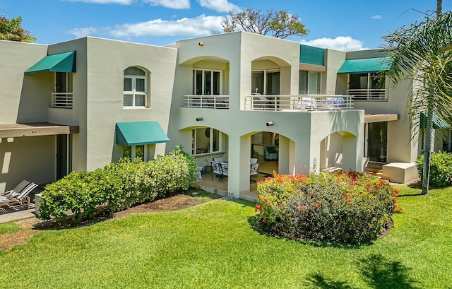 rear view of house featuring a yard, a balcony, and a patio area