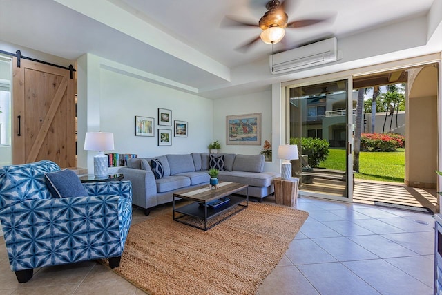 living room with an AC wall unit, a barn door, ceiling fan, and tile patterned flooring