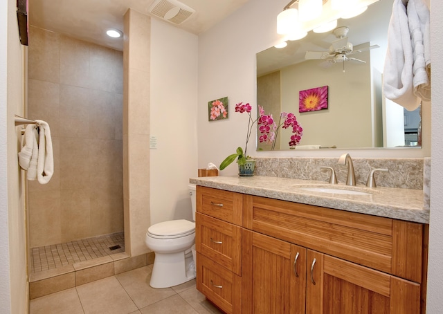 bathroom featuring tile patterned flooring, vanity, tiled shower, ceiling fan, and toilet