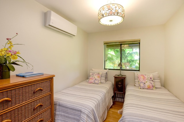 bedroom featuring a wall mounted AC and light hardwood / wood-style flooring