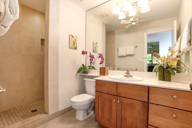 bathroom with ceiling fan, tile patterned flooring, tiled shower, vanity, and toilet