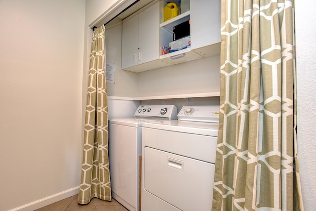 washroom with light tile patterned floors, washing machine and dryer, and cabinets