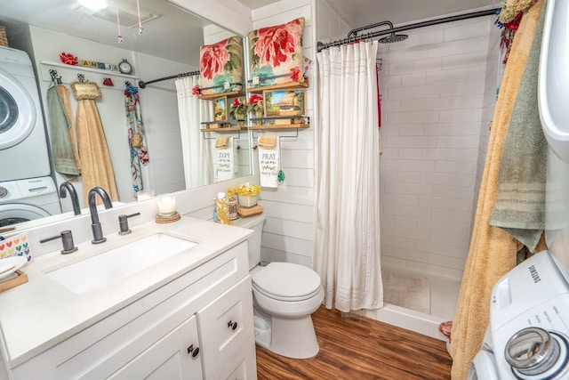 bathroom featuring vanity, stacked washer and dryer, toilet, curtained shower, and wood-type flooring