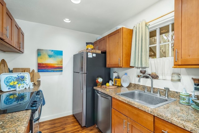 kitchen with light stone counters, dark hardwood / wood-style flooring, sink, and appliances with stainless steel finishes