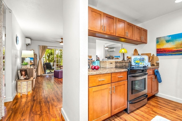 kitchen featuring light stone counters, light hardwood / wood-style flooring, ceiling fan, and stainless steel electric range