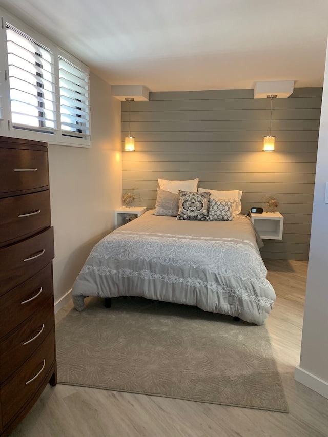 bedroom featuring light wood-type flooring and wooden walls