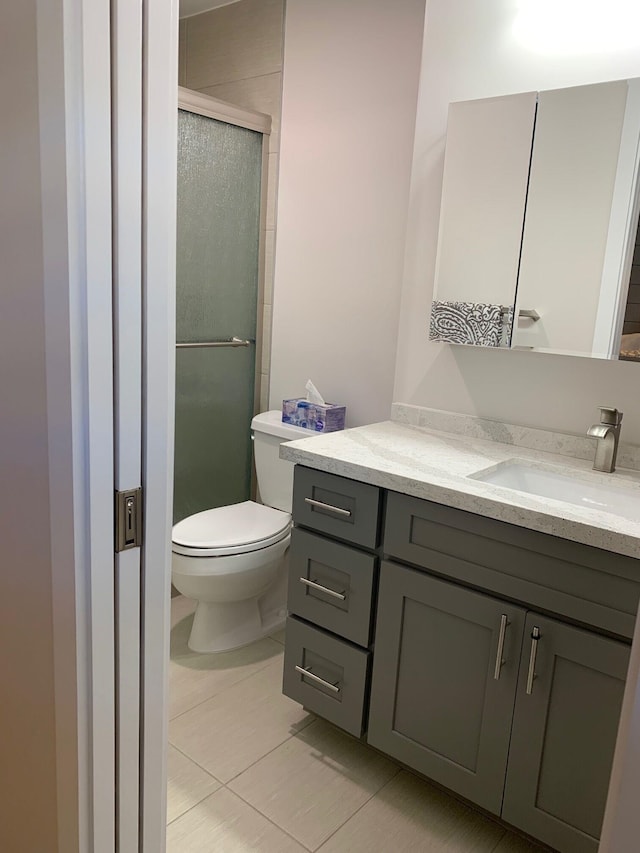 bathroom with tile patterned flooring, vanity, toilet, and a shower with shower door