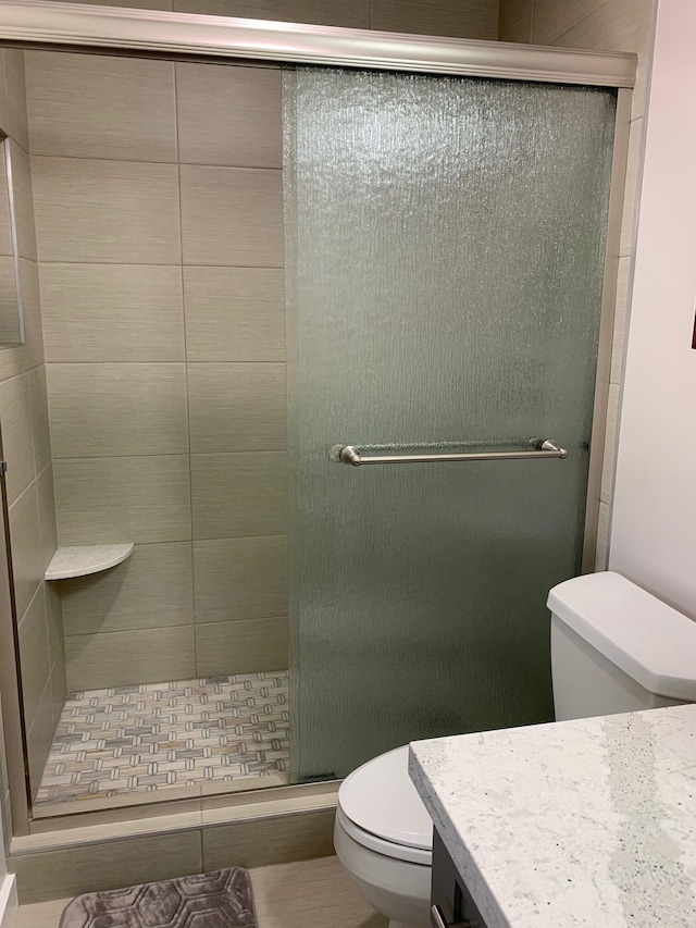 bathroom with an enclosed shower, vanity, and toilet