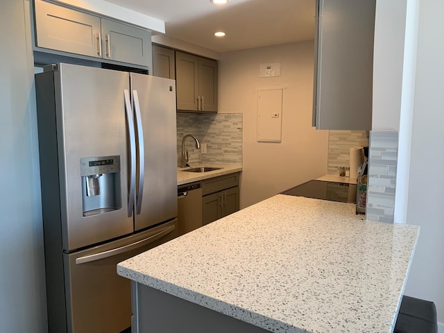 kitchen featuring gray cabinetry, light stone countertops, sink, backsplash, and appliances with stainless steel finishes