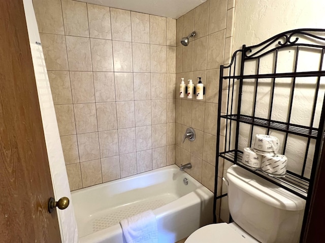 bathroom featuring a textured wall, toilet, and shower / tub combination