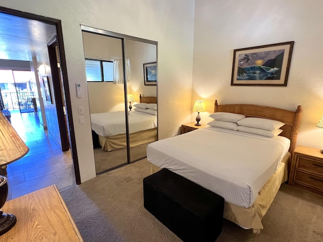 bedroom featuring multiple windows, carpet, a closet, and a textured wall