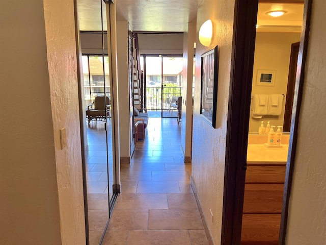 corridor with tile patterned floors, baseboards, and a textured wall